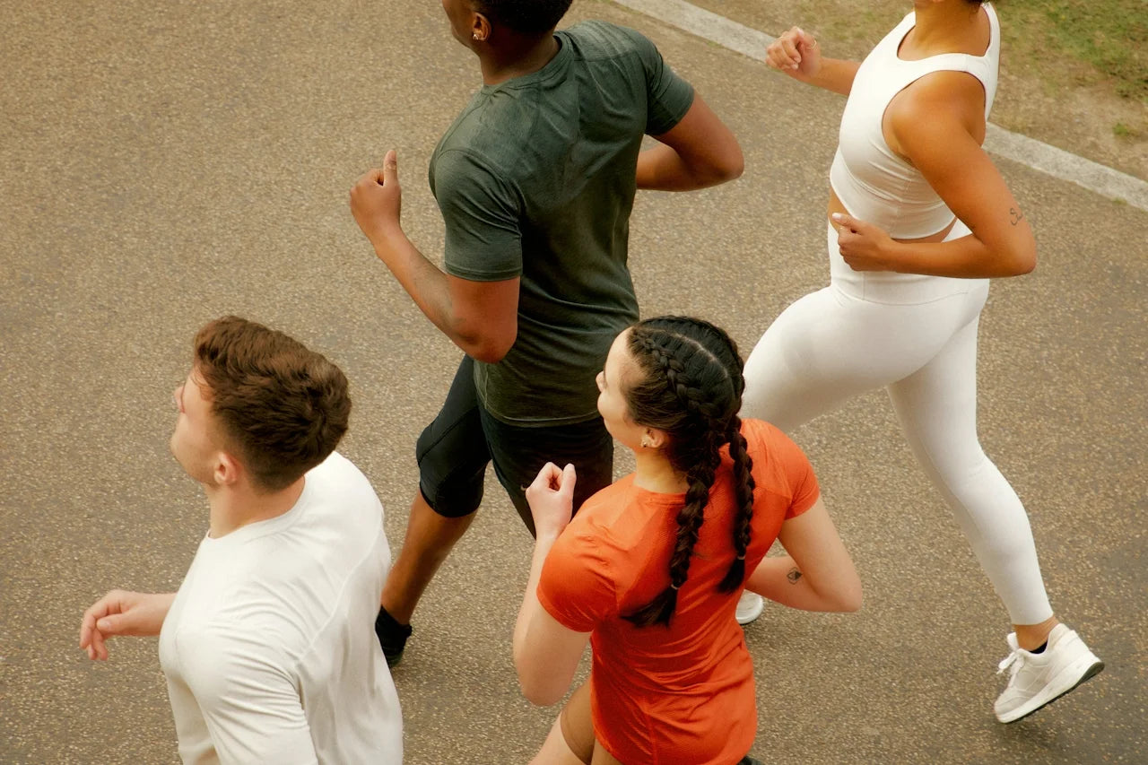Vier Personen joggen nebeneinander auf einem asphaltierten Weg.